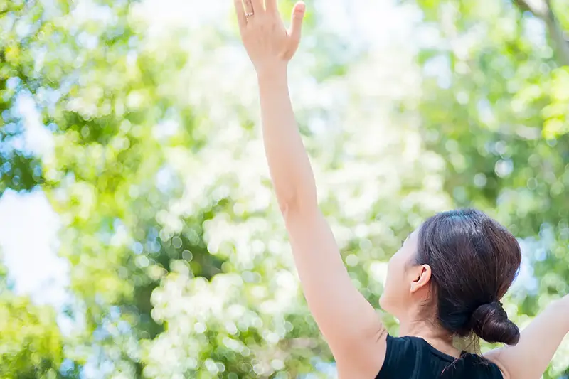 木漏れ日で伸びをする女性